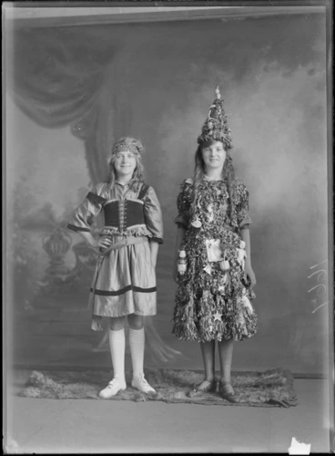 Image: Studio portrait of two unidentified girls, dressed in fancy dress costumes, including one dressed as a Christmas tree, probably Christchurch district