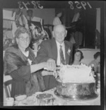 Mr and Mrs Abraham Harris cutting cake on the occasion of their 60th wedding anniversary, including band in background