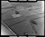 Leamington, Waikato District, view of fields mown with haystacks, tree windbreaks, fields with crops surround, power line pylons and access road foreground