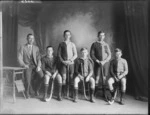 Studio portrait of unidentified boys' hockey team in uniform with hockey sticks and coach, Christchurch