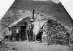 Two Chinese miners with Reverend George McNeur outside a stone house near Arrow Falls