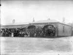 Members of a band and a group of people standing outside outside the house of Charles Waitara, at Parihaka
