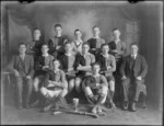 Studio portrait of unidentified men's hockey team and coaches, probably Christchurch district, includes cup and hockey sticks in front