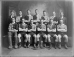 Studio portrait of unidentified men's hockey team in uniforms with pads, hockey sticks and small cup in front, Christchurch