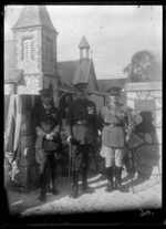 Army Officers in full military uniforms with medals and flag, outside a church with monument to fallen local WWI soldiers, Pakipaki, Hawke's Bay District