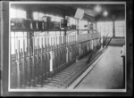 Inside a [tram?] signal box with mechanical levers in foreground with tram line numbers and names, probably Christchurch region