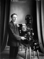 Motion picture projectionist alongside a projector