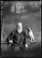 Studio portrait of unidentified elderly man with a large beard sitting with a small pug dog on a table, Christchurch