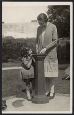 Miss Wilson, and child, by a sundial, Wellington Free Kindergarten, Taranaki Street, Wellington - Photograph taken by Robson and Boyer