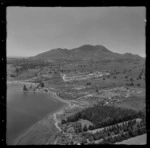 Large residential property with jetty and pine plantation at Rainbow Point, Lake Taupo, with Two Mile Bay, Lake Terrace road with housing developments and Mount Tauhara beyond