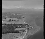 Large residential property with jetty and pine plantation at Rainbow Point, Lake Taupo, with Lake Terrace road, Wharewaka settlement and Mount Ruapehu beyond