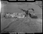 Nelson Freezing Works buildings on beach foreshore next to a creek and road with farmland beyond, Nelson Region