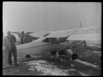 Group of unidentified men removing frost from the wing of a Mount Cook Air Services Ltd, Auster aircraft during the preparation for the Antarctic Expedition, Mount Cook
