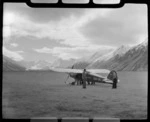 Mount Cook Air Services Auster ZK-BLZ Ski Plane on the Hermitage Airfield with [Harry Wigley?] and unidentified men, with snow covered mountains beyond, Mount Cook National Park, Canterbury Region
