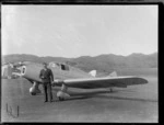An unidentified man standing next to a Miles M11 Whitney Straight aeroplane, at an unidentified aerodrome