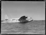Short Empire flying boat 'Aotearoa' ZK-AMA, skimming across water in unidentified harbour