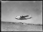 Short Empire flying boat ZK-AMC, in flight over an unidentified harbour