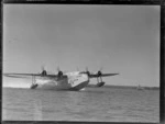 Short Empire flying boat 'Aotearoa' ZK-AMA, skimming across water on an unidentified harbour