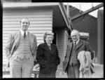 Portrait of (L to R) Mr and Mrs N Higgs with H W Worrall (Air Travel) in front of a wooden building, Rongotai Airport, Wellington
