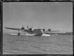 View of TEA's Short Empire Flying Boat 'Awarua' [taking off?] from Mechanics Bay, Auckland Harbour