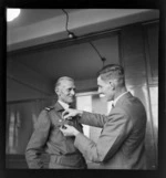 An unidentified man pinning a badge on Sir Keith Park