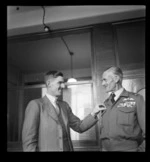 An unidentified man pinning a badge on Sir Keith Park