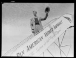 Portrait of John Gaffage, 'Chips' Rafferty, an Australian movie star, on a Pan American Airways plane boarding steps, Whenuapai Airfield, Auckland