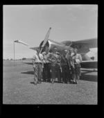 An unidentified group portrait in front of a bi-plane, Onerahi Aerodrome, Whangarei, Northland region