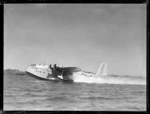 Flying boat 'Aotearoa' ZK-AMA, of Tasman Empire Airways, taxiing across harbour, location unidentified