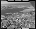 Downtown Dunedin City with railway yards and wharves, looking to the suburb of Andersons Bay with Saint Clair Beach beyond