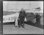 Mr A McIntosh with a small child, in front of an Auster ZK-AOB airplane, Invercargill