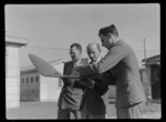 Portrait of (L to R) Mr A P S Bell (Secretary NZ Airline Pilots Association) with C Griffiths and F D Bethwaite of TEAL, examining a model aircraft wing, [Mechanics Bay, Auckland City?]