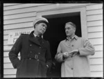 Portrait of (L to R) engineer Mr W Burns and NZ NAC Flying Officer Mr H Manghan, awaiting the arrival of Bristol Freighter 'Merchant Venturer' G-AIMC transport plane, Whenuapai Airfield, Auckland