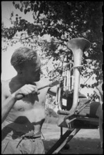 J B Collins repairs instrument of 5 New Zealand Brigade Band on the Adriatic sector, Italy, World War II - Photograph taken by George Kaye