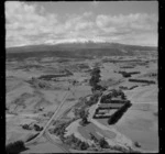 View over farmland with roads, rail and farm buildings north of the town of Ohakune to Mount Ruapehu in cloud beyond, Manawatu-Whanganui Region