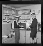 Two unidentified Sea Scouts washing dishes in a kitchen, location unidentified