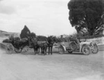 Men riding in a horse-drawn wagon and a motorcar