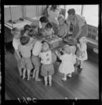 Levin Training Farm for handicapped children with unidentified children and teachers grouped around a tape recorder within a classroom, North Wellington Region