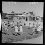 Levin Training Farm for handicapped children with unidentified children and teachers playing catch with a ball in front of the school, North Wellington Region