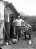 Man, outside a hut in the gum fields, holding loaves of bread