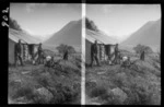 Edgar Williams and three unidentified men on a hunting trip, possibly Williams family members, with rifles and antlers, beside a stone hut in a river valley