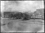 A timber yard with piles of sawn timber, and a cart in the foreground.