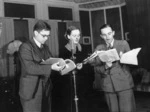 Don Priestley, Sinclair Breen and Ralph Hogg reading a script in a studio during a broadcast