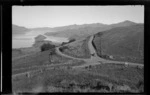 View of Duvauchelle Bay and Barry's Bay, including hills and car at cross roads, Duvauchelle area, Banks Peninsula, Canterbury