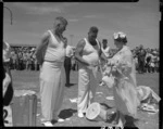 Her Majesty Elizabeth, the Queen Mother, examining a woodchopping competitor's axe at a civic welcome in Napier