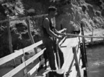 Unidentified man holding the rope of the Queen Charlotte Sound mail launch at East Bay, Arapawa Island