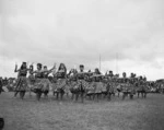 Burns, G, fl 1958 (Photographer) : Women performing an action song with patu at centenary celebrations of the King Movement, Turangawaewae Marae, Ngaruawahia