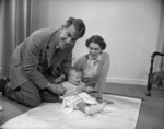 Sir Edmund Hillary, his wife Louise, and their infant son Peter, with a map of Antartica