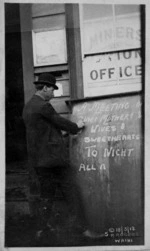 Man writing a sign announcing a meeting during the Waihi miners' strike