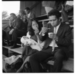 Opunake, young couple in grandstand; rugby game in sports grounds